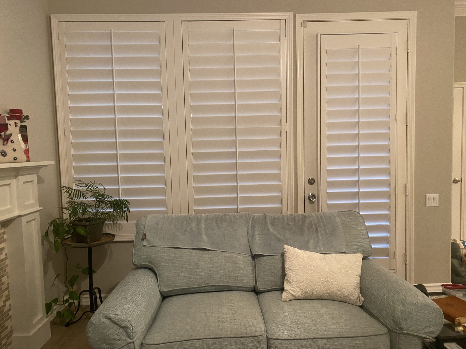 Wide bank of white plantation shutters across a living room window
